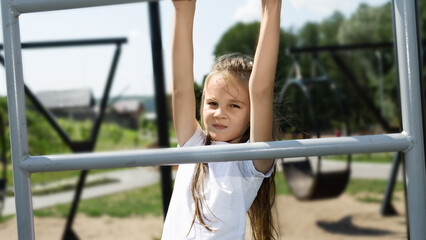 An active child plays rock climbing on the playground of the school yard.. little girl climbing on stairs at playground