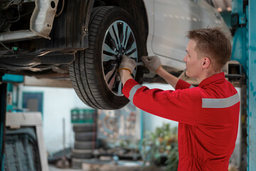 Young caucasian repairman analyzing and fixing broken car in car repair mechanic shop