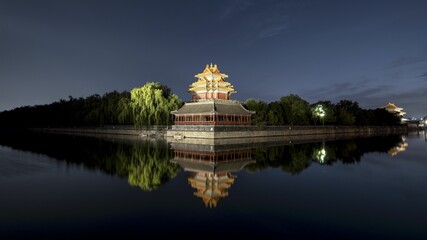 Fototapeta na wymiar Grand Palace Museum building with greenery surrounding the edges reflected in water at night