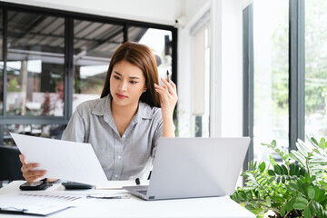 Young thoughtful Asian business woman executive manager wearing shirt working in modern office,...
