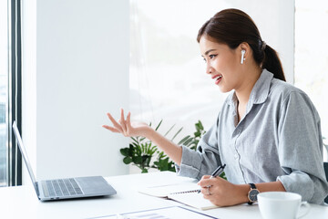 business woman talking about sale report in video conference. Asian team using laptop and tablet...