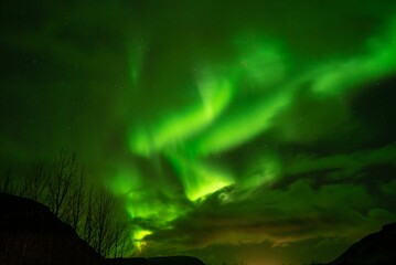 Obraz na płótnie Canvas Stunning night sky view of a green, illuminated Aurora Borealis waves