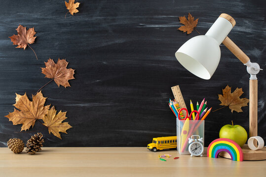 Get ready for the school year with this high-angle view photo featuring an array of school supplies and desk lamp on blackboard isolated background. Add your text or advert in the copy-space