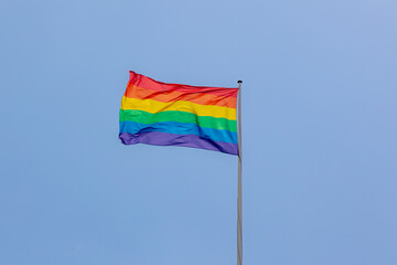 Celebration of pride month, Colourful rainbow flag waving in the air with blue clear sky...