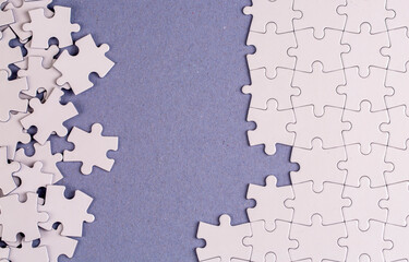 Missing jigsaw puzzle pieces. Business concept. Fragment of a folded white jigsaw puzzle and a pile of uncombed puzzle elements against