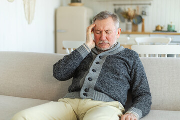 Headache pain. Unhappy middle aged senior man suffering from headache sick rubbing temples at home. Mature old senior grandfather touching temples experiencing stress. Man feeling pain hurt in head
