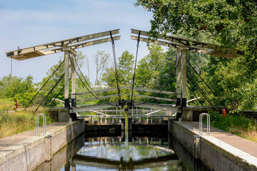 Spring landscape with view of traditional and typical Dutch style white wooden bridge crossing canal in Amsterdamse Bos (Forest) A park in the municipalities of Amstelveen and Amsterdam, Netherlands.