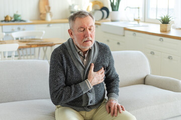 Pain on heart, heart attack. Unhappy middle aged senior man suffering from chest pain heart attack problems with health at home. Mature old senior grandfather touching chest experiencing infarction