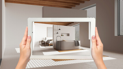 Augmented reality concept. Hand holding tablet with AR application used to simulate furniture and design products in empty wooden interior, japandi minimal bedroom and bathroom