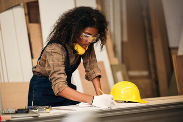 African American Woman in Safety Hardhat Working in Furniture Factory, Small Business Owner Female Carpenter Working Wood Work in Carpentry Workshop.