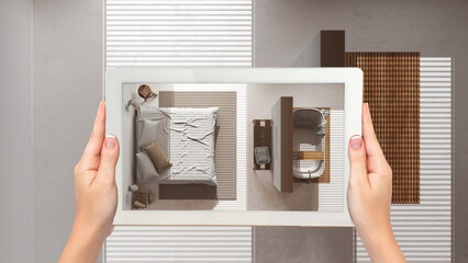 Augmented reality concept. Hand holding tablet with AR application used to simulate furniture and design products in empty wooden interior, minimal bedroom and bathroom, top view