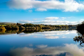 Tranquil lake reflecting the white clouds in the sky, creating a peaceful atmosphere. Bolton, UK.
