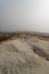 Barren desert landscape situated on the edge of a steep cliff, shrouded in a dense layer of fog