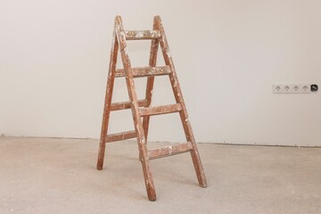 Vintage wooden ladder against a smooth white wall in an unoccupied room