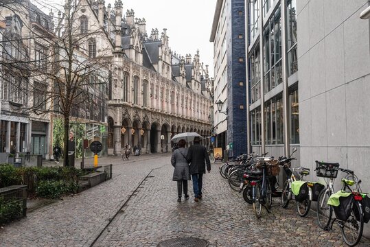 Middle aged couple walking a city street under a umbrella on a rainy day. Taken in Mechelen, Belgium.