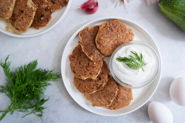 Zucchini pancakes with sour cream and herbs. Vegetarian food, proper nutrition.