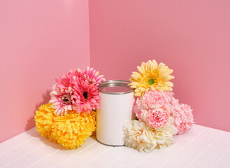 A white can of paint among brightly colored flowers on a pink background. Idea of fashion home design.