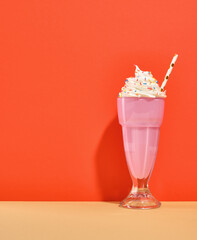 Pink, fresh, bright milk shake with white whipped cream and sprinkles. Copy space for text. Composition of birthday decoration.