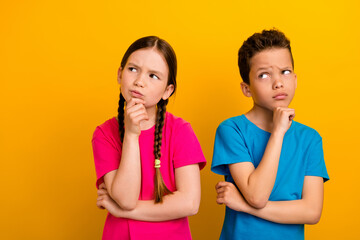 Photo of sweet doubtful preteen schoolchildren wear t-shirts hands arms chins looking empty space isolated yellow color background - obrazy, fototapety, plakaty