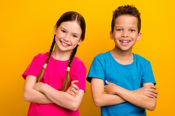 Photo of confident cool preteen schoolchildren wear t-shirts smiling arms crossed isolated yellow color background