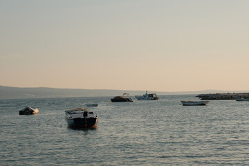 Fototapeta na wymiar Golden Hour Serenity: Small Boats in Sea at Sunset