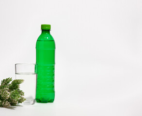 Shortage of water. Green plastic water bottle, a glass cup with clean drinking water. Copy space for text.