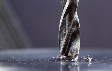 metal drill bit with lubrication oil liquid make holes in steel billet on industrial drilling machine. Metal work industry