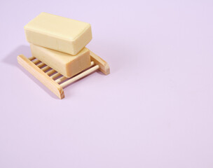 Two natural pieces of soap lie on wooden soap dish in the shape of a lattice. Accessories for spa. Copy space for text.