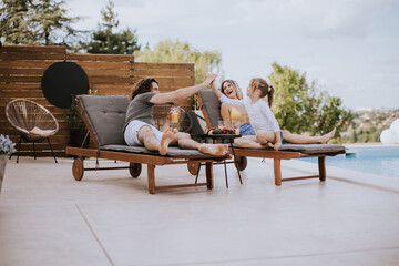 Family with a mother, father and daughter sitting on the deck chairs by the swimming pool
