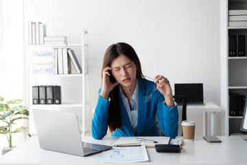 Tired and stressful Asian office worker having a hard time trying to focus on her work, feeling tried after working a long day.