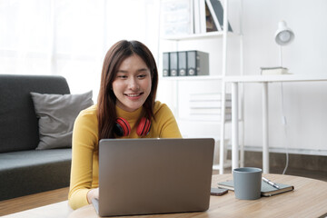 Naklejka premium Young beautiful Asian woman using laptop computer, relaxing in her free time in the living room.