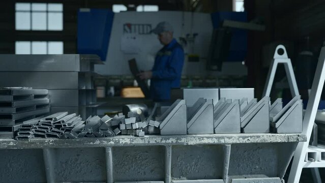 Metal parts on factory table with working assembler. Creative. Worker assembles factory machines with metal parts. Various metal parts for assembling factory machines