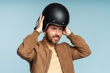 Handsome bearded biker wearing motorcycle helmet isolated on blue background