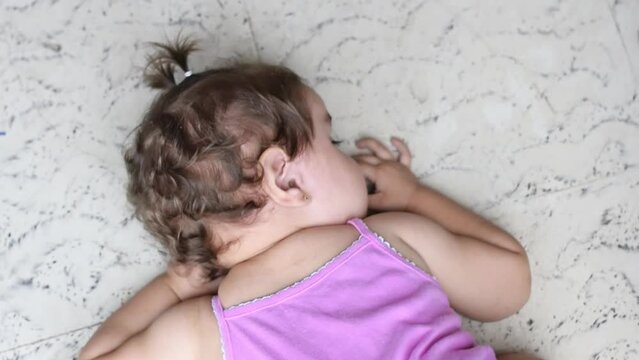 Top-down shot of a little baby lying on the floor face down, throwing a tantrum