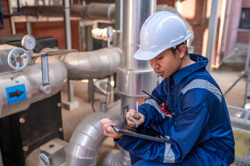 Young engineer working at large factory,Technician in protective uniform and with hardhat  checking temperature in pipes
