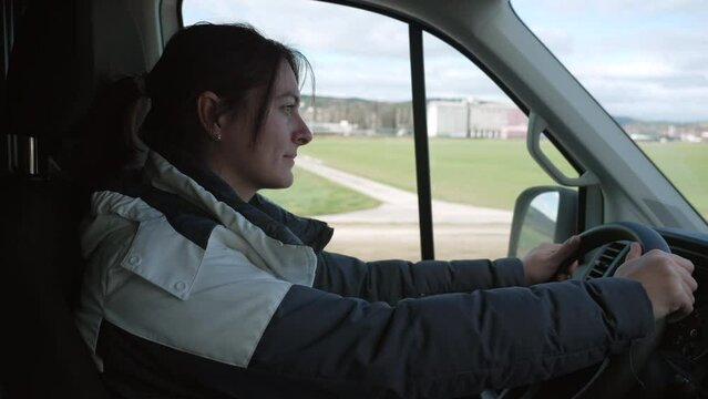 Happy woman driving rental truck. Family moving to a new home. Female driver holding steering wheel drives on road
