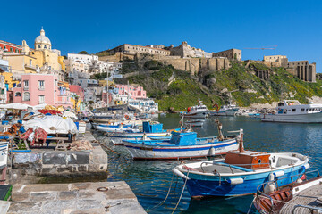 Fish nets and colorful fishing boats moored at Corricella port in Procida, Campania, Italy