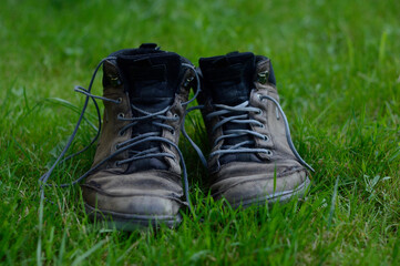 pair of old torn leather boots on green grass