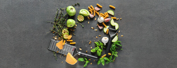 Dry pasta, grater, cheese and vegetables on grey background