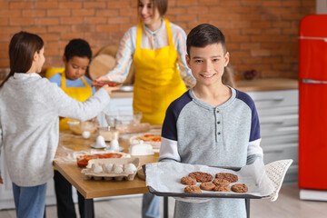Little boy with prepared cookies during cooking class in kitchen