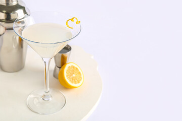 Glass of tasty martini, jigger, shaker and lemon on white background