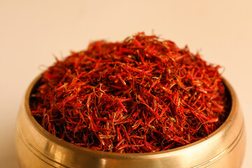 Fototapeta premium Golden bowl and spoon with pile of saffron on light background