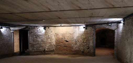 Spooky basement with pipe. red brick wall and wet tiled floor. Building under construction red brick wall . historical house. electrical wiring in corrugated pipe. arched doorway.