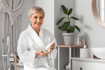 Mature woman applying hand cream in bathroom