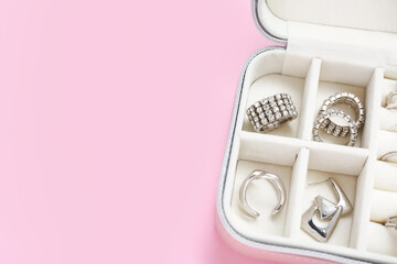 Opened organizer with stylish silver rings on pink background