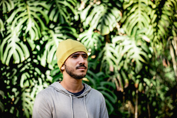 Joyful Solitude: Young Man with Thoughtful Smile Amidst Lush Foliage