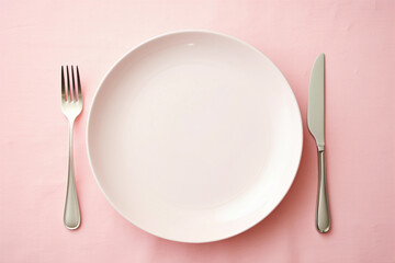 Empty white plate on a pastel pink table. Top view. Background for mockup and product presentation. Kitchen utensils.