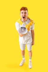 Young redhead man shouting into megaphone on yellow background