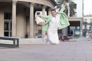 Fototapeta premium Young woman dressed up girl jumping for happiness on the street.