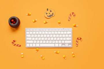 Composition with modern computer keyboard and tasty candy corns for Halloween on orange background